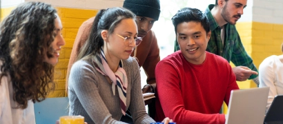 Diverse group of young professionals working together on laptops in a co-working space, representing open digital resources and knowledge sharing
