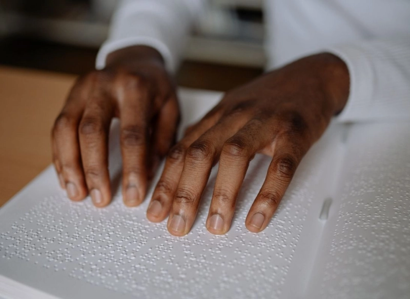 Nahaufnahme von Händen, die ein Braille-Buch lesen, als Symbol für barrierefreie und inklusive Bildung.
